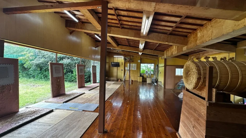 Wooden training hall at Sasagawa dōjō in Chiba, Japan, with practice targets and windows opening onto a garden.